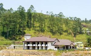 a large white house with a hill in the background at Talawakele Rest House in Nuwara Eliya +85 photos