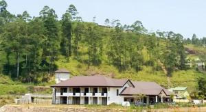 a large white house with a mountain in the background at Talawakele Rest House in Nuwara Eliya