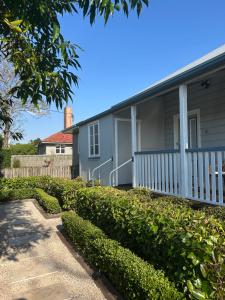 a gray house with a white porch and bushes at Eton Cottage - Central Boutique Stay in Toowoomba