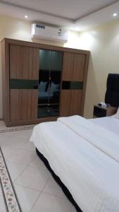 Un dormitorio con una cama blanca y un armario de madera. en Ziena Hotel, en Abu Dabi