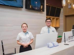 a man and a woman standing next to a table with a computer at City Comfort Inn Hechi Tian'E Bus Terminal 