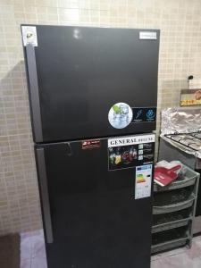 a black refrigerator in a kitchen with stickers on it at الرائد للشقق المفروشة in Amman