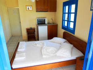 a bedroom with a bed with a microwave and a kitchen at Mouragio Studios in Tyros