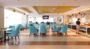 a restaurant with blue chairs and tables and people in the kitchen at Howard Johnson by Wyndham Life Changrong in Qinzhou