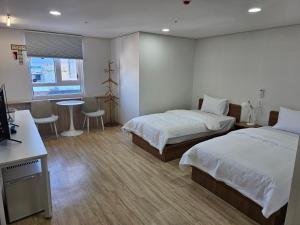 a hotel room with two beds and a table at Gyeingju Bonghwang INN in Gyeongju