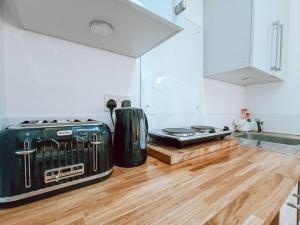Una cocina con horno tostador y suelo de madera. en The Pembroke Studio By Richmond Park, en Kingston upon Thames 11 fotos más