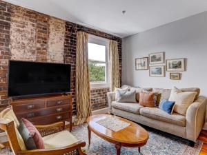 Una sala de estar con un sofá y un televisor. en Above Broughton St 3002, en Savannah