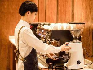 a man is standing next to a blender at James Joyce Coffetel Xinyang Municipal Government Railway Station in Xinyang