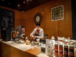 a woman preparing food at a counter in a restaurant at James Joyce Coffetel Luoyang Longmen High-speed Railway Station Baolong Plaza in Luoyang