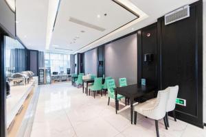 a dining room with green chairs and a table at Xana Hotelle Binzhou Yangxin in Binzhou