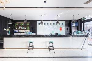 a bar with two stools in front of a counter at Xana Hotelle Binzhou Yangxin in Binzhou