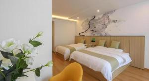 a bedroom with two beds and a yellow chair at Vatica Hotel Huangshan South Gate Terminal Station in Huangshan Scenic Area +41 photos
