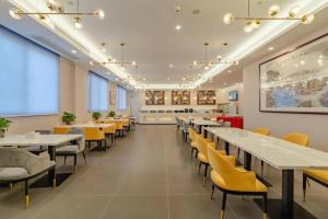 a dining room with tables and yellow chairs at Green Tree Inn Anhui Suzhou Evergrande in Suzhou