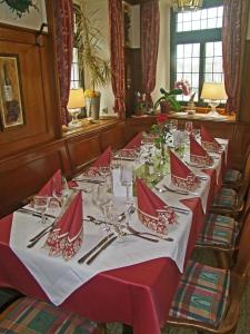 uma mesa longa com guardanapos vermelhos e talheres de prata em Hotel Beller em Kenzingen