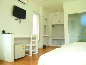 a bedroom with a bed and a desk with a tv on the wall at Banmon Makok in Ban Makok
