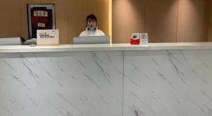 a man is sitting at a counter with a laptop at Green Tree Inn Express Huainan Xiejiaji District Orient Guangji Hospital in Huainan