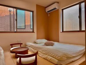 a bedroom with a bed and a table and two windows at S3涉谷中心 交通枢纽 涉谷车站6分钟 无限视野 最大2人 Shibuya center 6 mins to ST Max 2P 直达新宿 涉谷 表参道 品川 池袋 上野 代代木 银座 原宿 in Wada