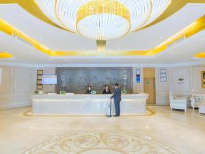 a man standing at a counter in a hotel lobby at Vienna Hotel Hubei Xiangyang Tang City Gulou in Xiangyang
