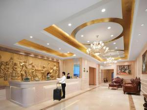 a man standing in a lobby with a suitcase at Vienna Hotel Shandong Dezhou Government Shopping Plaza in Dezhou