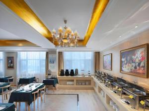 a dining room with tables and chairs and a chandelier at Vienna Hotel Shandong Dezhou Government Shopping Plaza in Dezhou