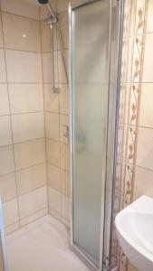 a shower with a glass door next to a sink at Pokoje Gościnne Pod Grapą in Poronin