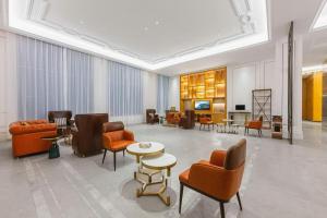a lobby with orange chairs and tables in a building at Vienna Hotel Qinghai Dachaidan in Da Qaidam