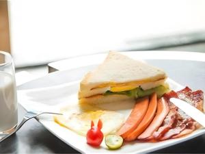a sandwich and vegetables on a plate on a table at Gya Hotel Beijing Shunyi Yanjing Bridge in Beijing