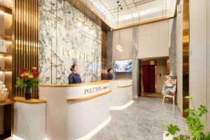 a woman standing at a reception desk in a lobby at Poltton International Service Apartment Shanwei Urban District High-speed Railway Station in Shanwei