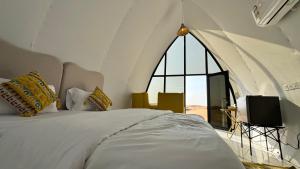 a bedroom with a bed and a large window at Moon Light Camp in Badīyah