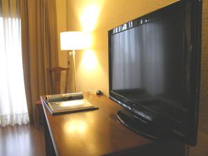 a flat screen tv sitting on top of a wooden desk at Oca Ipanema Hotel in Vigo