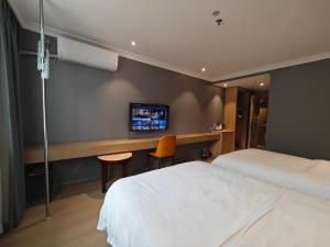 ein Hotelzimmer mit zwei Betten und einem Fernseher in der Unterkunft Sainan Hotel, Guangzhou Zhongda Lujiang Subway Station Branch in Guangzhou
