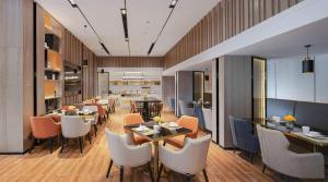 a restaurant with tables and chairs in a room at Echarm Hotel Shenzhen International Exhibition Center Fuyong in Shenzhen