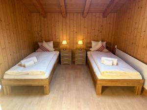 two twin beds in a room with wooden walls at Villa Eiger Close to Grindelwald in Lütschental