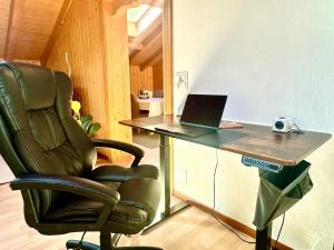 a office with a chair and a desk with a laptop at Villa Eiger Close to Grindelwald in Lütschental