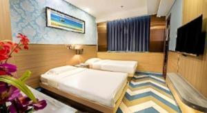 a bedroom with two beds and a flat screen tv at Hou Kong Hotel in Macau