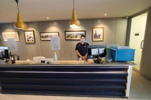 a man with a face mask standing behind a counter at Pakchong Center Poshtel in Mu Si
