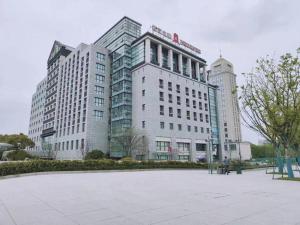a large white building with two tall buildings at Jinjiang Inn Jiaxing South Lake in Jiaxing