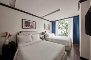 a hotel room with two beds and a window at The Passion Suites Hotel & Spa in Ho Chi Minh City