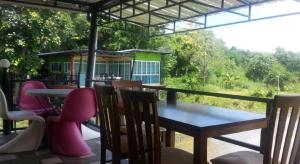 einen Tisch und Stühle auf einer Veranda mit einem Haus in der Unterkunft BanRai ChernMa Resort in Tak