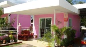 a pink house with a white roof at Baan Gon Chompu in Ratchaburi