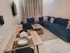 un salon avec un canapé bleu et des tables dans l'établissement Studio Luxe Nouaceur, à Nouaseur