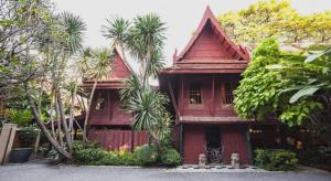 a red house with palm trees in front of it at Buddy Place in Bangkok