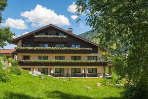 a large house on top of a green hill at Boutique Hotel Herzhof - Garni-Appartements - Adults Only in Riezlern
