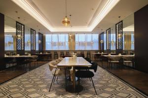 una sala da pranzo con tavoli, sedie e finestre di Jinjiang Metropolo Shaoxing Keqiao Wanda Plaza a Shaoxing