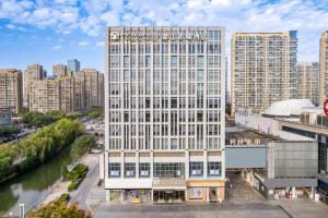 un alto edificio bianco vicino a un fiume di Jinjiang Metropolo Shaoxing Keqiao Wanda Plaza a Shaoxing