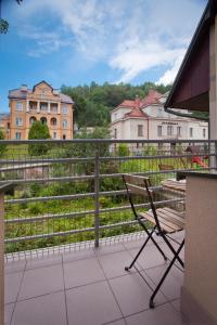 un banc assis sur un balcon donnant sur un champ dans l'établissement Trzy Siostry, à Krynica-Zdrój