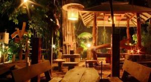 un patio con un tavolo di legno e panche di notte di Tambai Resort a Phang Nga