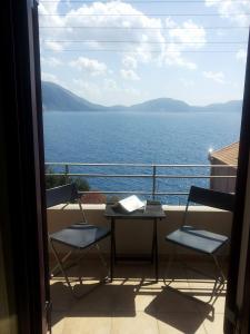a balcony with chairs and a table and a view of the water at Cosis Inn in Asos