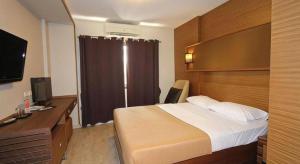 a bedroom with a bed and a desk with a television at Honey Lodge in Pattaya South
