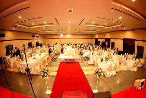 un gran salón de banquetes con mesas blancas y alfombra roja en Royal Diamond Hotel, en Phetchaburi